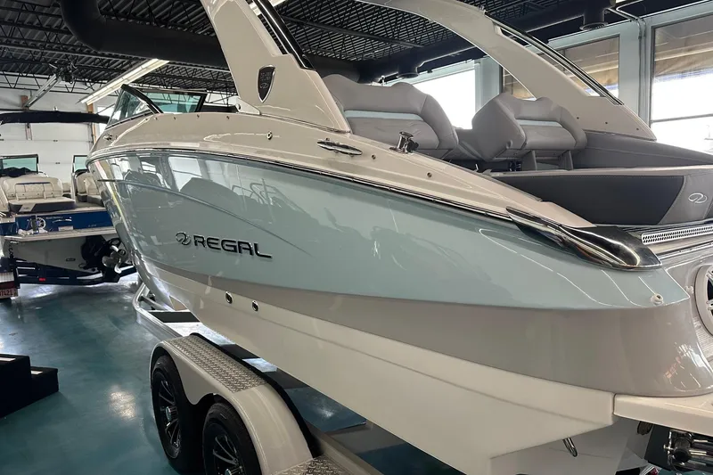 Slide: The Image of 2026 Regal LS4 boat in showroom, sleek design, white exterior, on trailer. - 2