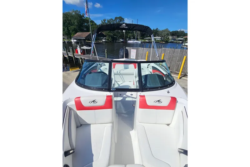 Slide: The Image of 2015 Monterey 197 Blackfin boat with red and white seating, docked by a lake. - 16
