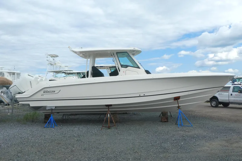 Slide: The Image of 2027 Boston Whaler 360 Outrage boat on stands, displayed outdoors under a cloudy sky. - 1