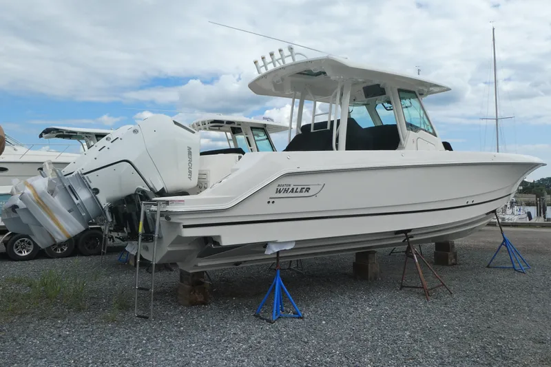 Slide: The Image of 2027 Boston Whaler 360 Outrage boat on stands, featuring twin Mercury engines. - 2