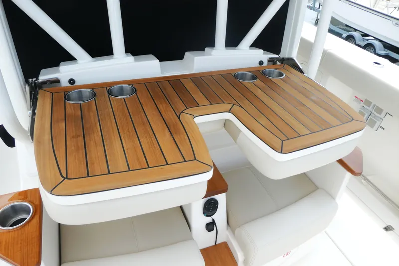 Slide: The Image of Luxury seating area on 2027 Boston Whaler 360 Outrage with wooden table and cup holders. - 7