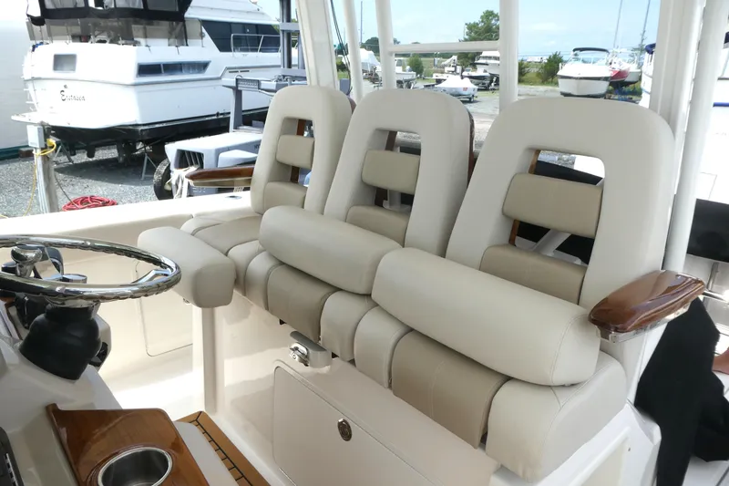 Slide: The Image of 2027 Boston Whaler 360 Outrage helm seating with luxurious beige upholstery and steering wheel. - 9