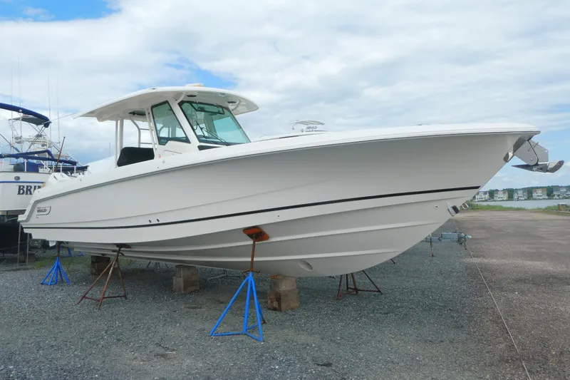 The Image of 2027 Boston Whaler 360 Outrage boat on stands, displayed outdoors on gravel. - 0