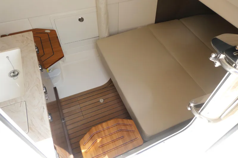 Slide: The Image of Interior cabin of 2027 Boston Whaler 360 Outrage with wooden flooring and beige seating. - 17