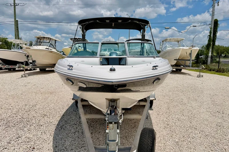 Slide: The Image of 2020 Regal 21 OBX boat on trailer, surrounded by other boats, under a partly cloudy sky. - 2
