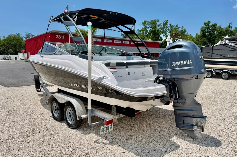 Slide: The Image of 2020 Regal 21 OBX boat with Yamaha outboard motor on a trailer, parked outdoors. - 7
