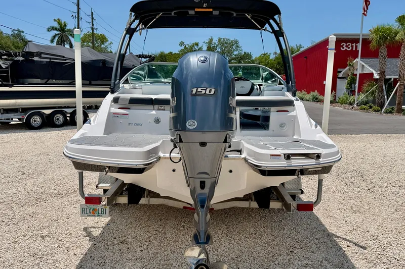 Slide: The Image of 2020 Regal 21 OBX boat with Yamaha 150 outboard motor, parked on gravel. - 6