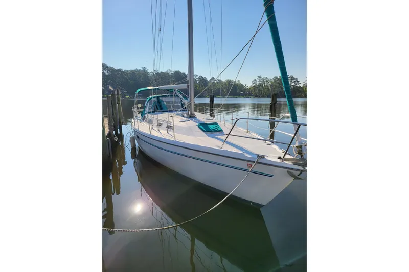 The Image of Sailboat Catalina 36 MkII 1997 docked on calm water, surrounded by trees. - 0