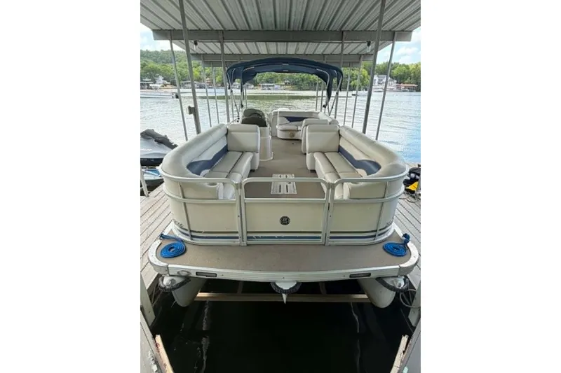 The Image of 2009 Premier 240 SunSpree pontoon boat docked under a covered slip on a lake. - 1