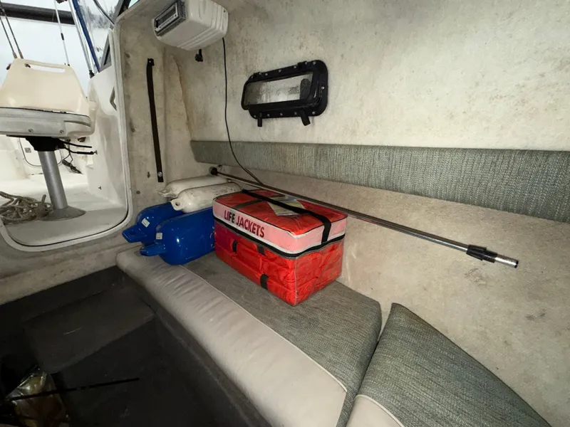 Slide: The Image of The interior of a 2000 Bayliner Trophy 2002FF features a bench with life jackets and fishing rods. - 25