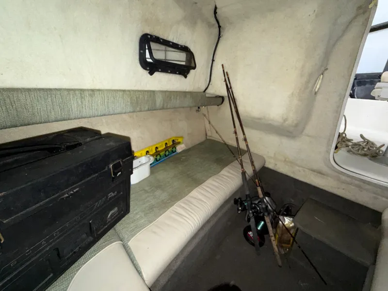 Slide: The Image of The image shows the interior of a 2000 Bayliner Trophy 2002FF boat. There's a bench seat, fishing rods, and a toolbox. - 24