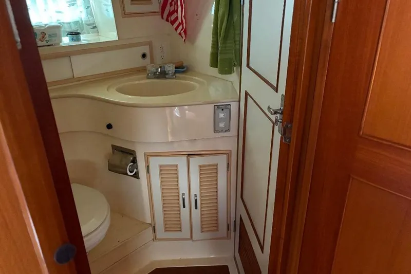 Slide: The Image of Bathroom interior of a 1990 Hi-Star Trawler, featuring sink, toilet, and wooden cabinetry. - 17