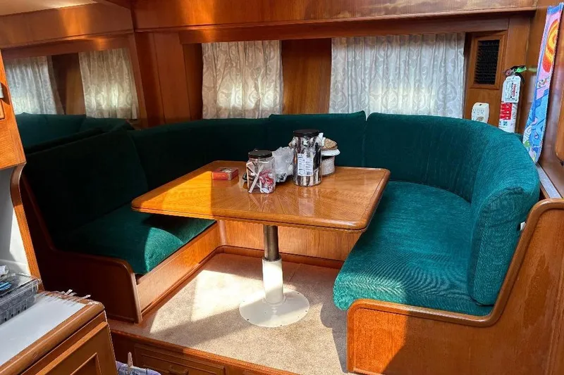 Slide: The Image of Interior of a 1990 Hi-Star Trawler with teal seating and wooden table. - 16