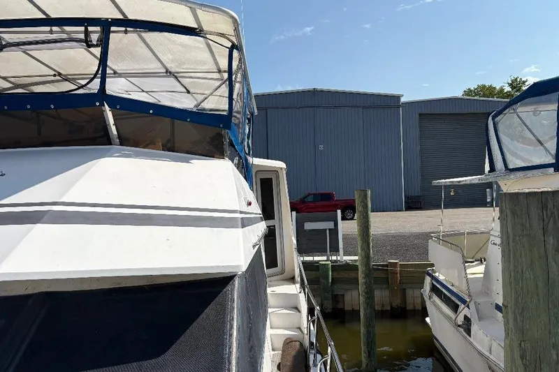 Slide: The Image of 1990 Hi-Star Trawler docked at marina with blue canopy and nearby boats. - 42