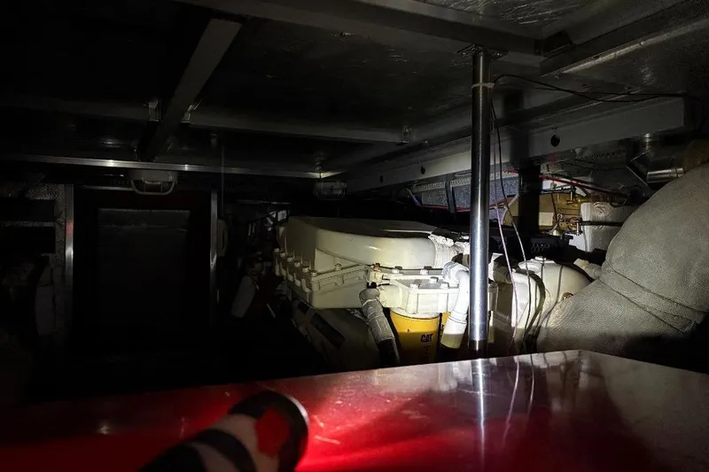 Slide: The Image of Dimly lit engine room of a 1990 Hi-Star Trawler, showcasing mechanical components and wiring. - 23