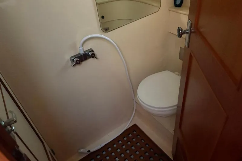 Slide: The Image of 1990 Hi-Star Trawler bathroom with toilet, shower hose, and wooden door. - 18