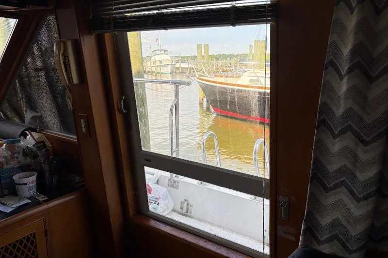 Slide: The Image of Interior view from a 1990 Hi-Star Trawler, overlooking a docked boat through a window. - 8