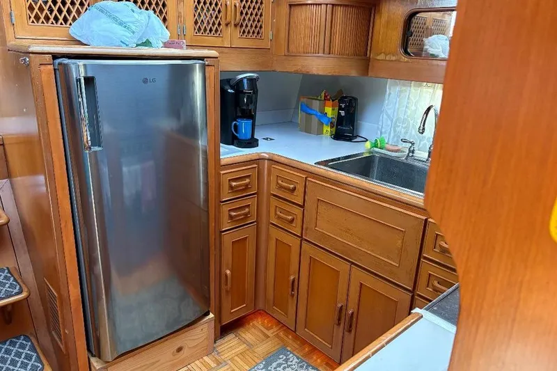 Slide: The Image of 1990 Hi-Star Trawler kitchen with wooden cabinets, stainless steel fridge, and sink. - 14