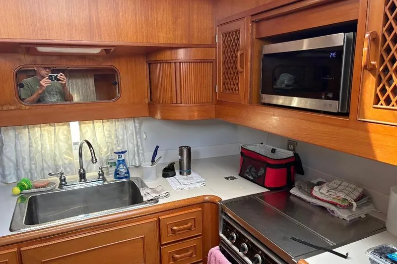 Slide: The Image of 1990 Hi-Star TRAWLER kitchen with wooden cabinets, stainless steel sink, and microwave. - 15