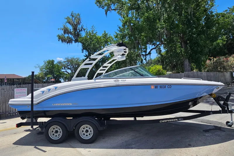 Slide: The Image of 2023 Chaparral 23 SSi boat on trailer, parked outdoors with trees in background. - 1