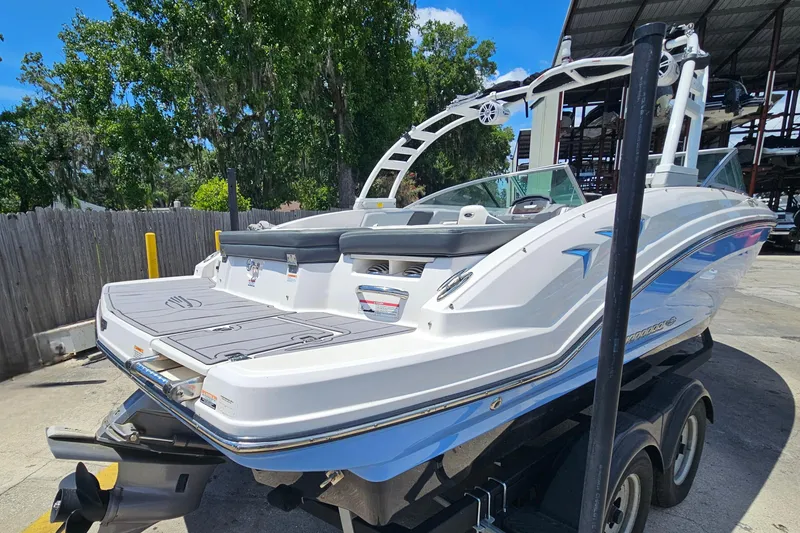 Slide: The Image of 2023 Chaparral 23 SSi boat on trailer, parked outdoors under clear blue sky. - 3