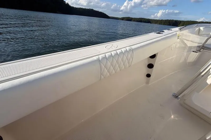 Slide: The Image of 2022 Sailfish 242 CC boat interior with cushioned seating, on a calm lake. - 8