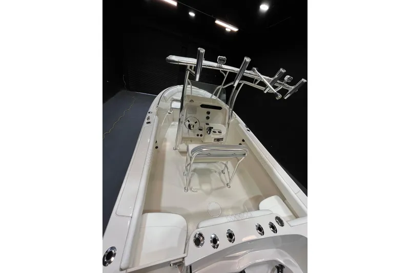 Slide: The Image of 2022 Sailfish 242 CC boat interior with helm, seating, and rod holders in a showroom. - 10