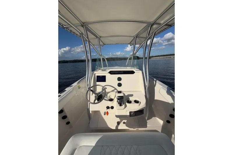 Slide: The Image of 2022 Sailfish 242 CC boat helm with steering wheel and controls on calm water. - 6
