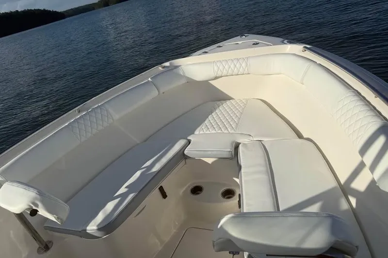 Slide: The Image of 2022 Sailfish 242 CC boat interior with white cushioned seating on calm water. - 3