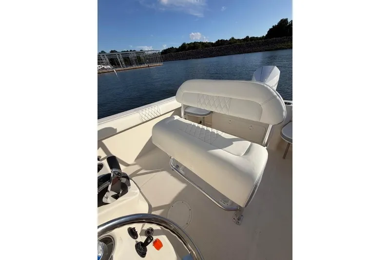 Slide: The Image of 2022 Sailfish 242 CC boat interior with white seating, steering wheel, and water view. - 5