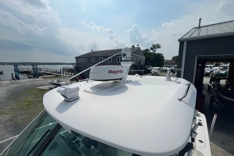 Slide: The Image of 2012 Boston Whaler 285 Conquest with Raymarine radar, docked near a marina under cloudy skies. - 18