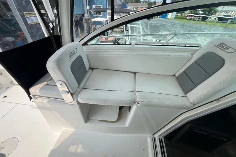Slide: The Image of 2012 Boston Whaler 285 Conquest boat seating area with white and gray cushions. - 13