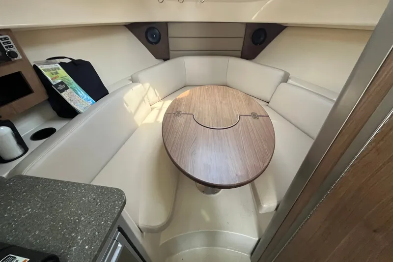 Slide: The Image of 2012 Boston Whaler 285 Conquest cabin with cozy seating and wooden table. - 3