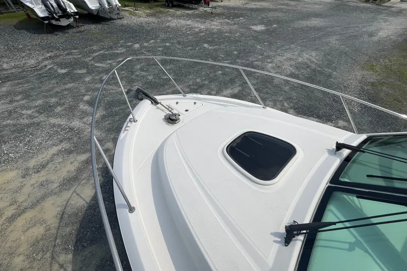 Slide: The Image of 2012 Boston Whaler 285 Conquest boat deck with railing and hatch, parked on gravel. - 19
