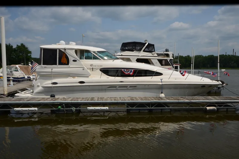 Slide: The Image of 2004 Sea Ray 480 Motor Yacht docked, decorated with flags, under a partly cloudy sky. - 4