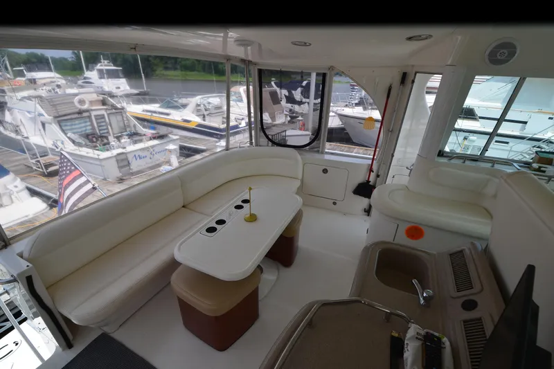 Slide: The Image of Interior of a 2004 Sea Ray 480 Motor Yacht with white seating and docked boats outside. - 17