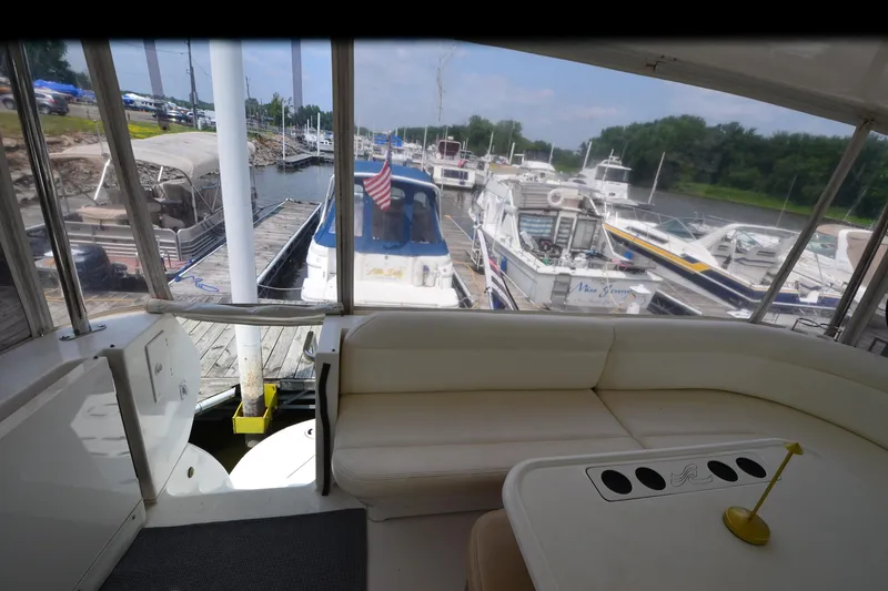 Slide: The Image of 2004 Sea Ray 480 Motor Yacht interior with marina view, featuring comfortable seating and docked boats. - 18
