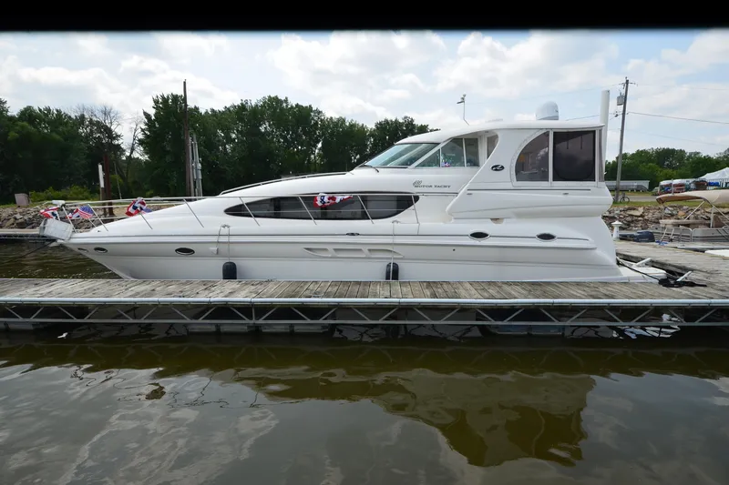 Slide: The Image of 2004 Sea Ray 480 Motor Yacht docked, featuring sleek design and festive flags. - 7