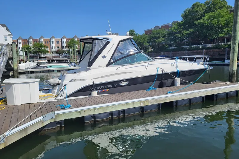 Slide: The Image of 2018 Monterey 335 Sport Yacht docked at a marina, surrounded by water and residential buildings. - 1