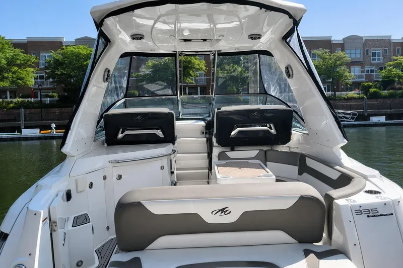 Slide: The Image of 2018 Monterey 335 Sport Yacht interior with seating, docked near waterfront buildings. - 2