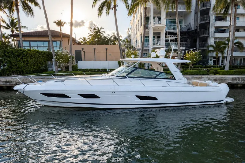 The Image of 2021 Intrepid 477 Evolution yacht docked by waterfront buildings and palm trees. - 0