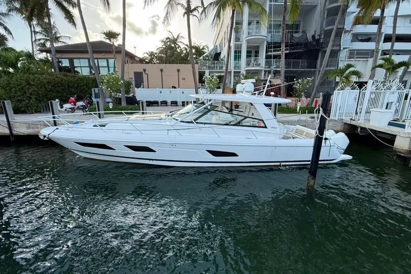 Slide: The Image of 2021 Intrepid 477 Evolution yacht docked by palm trees and waterfront homes. - 23