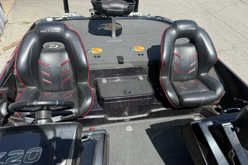Slide: The Image of 2021 Nitro Z20 boat interior with black and red seats, steering wheel, and deck. - 100