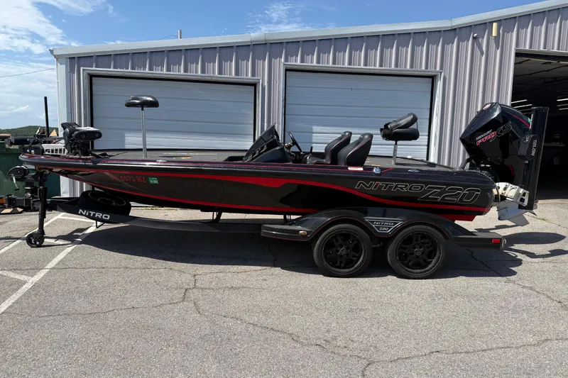 The Image of 2021 Nitro Z20 boat with trailer parked outside a garage on a sunny day. - 81