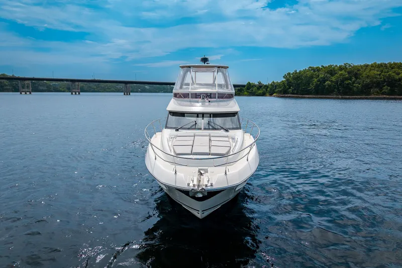 Slide: The Image of 2025 Pacific Prestige 460 Fly yacht on serene water with bridge and trees in background. - 6