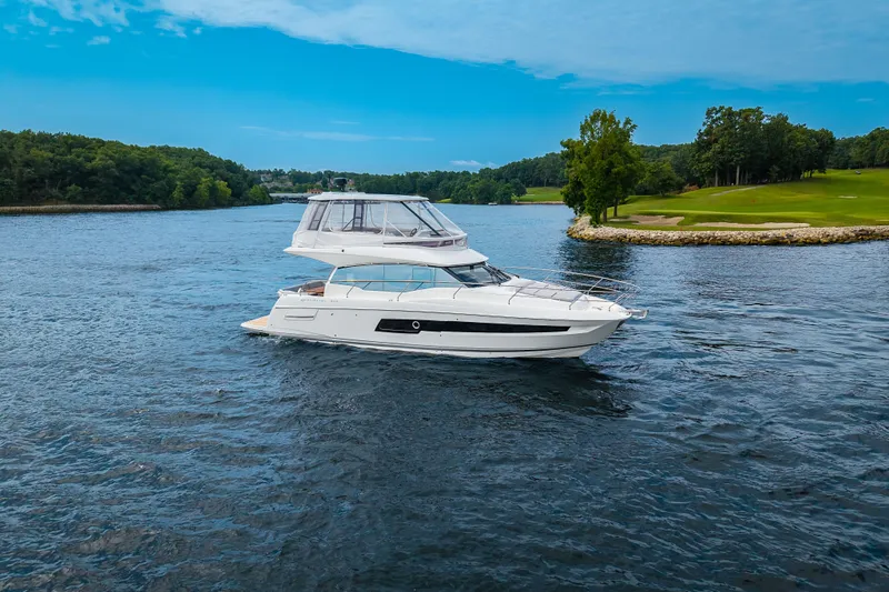 Slide: The Image of 2025 Pacific Prestige 460 Fly yacht cruising on a scenic lake with lush greenery. - 14