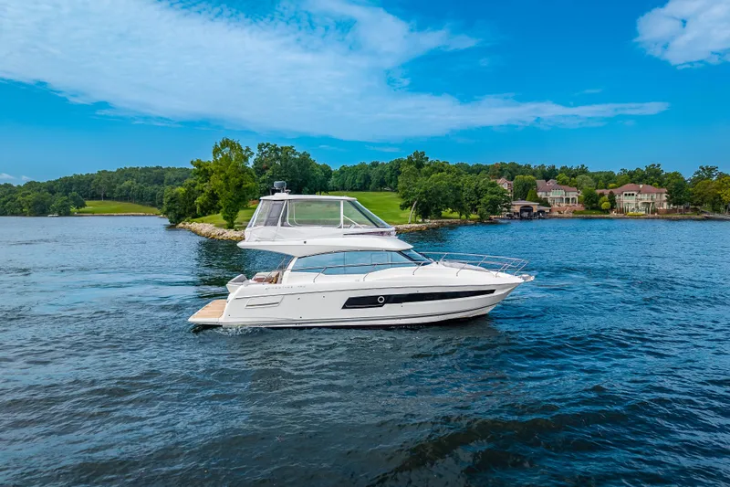 Slide: The Image of 2025 Pacific Prestige 460 Fly yacht cruising on a scenic lake with lush greenery. - 9
