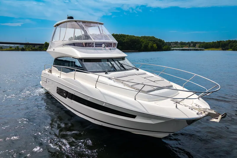 The Image of 2025 Pacific Prestige 460 Fly yacht cruising on a serene lake under a clear blue sky. - 0
