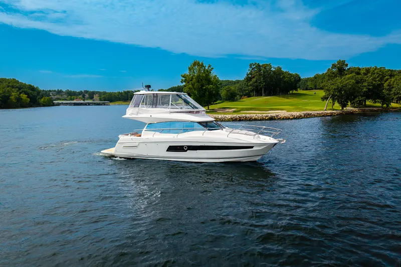 Slide: The Image of 2025 Pacific Prestige 460 Fly yacht cruising on a serene lake under a clear blue sky. - 16