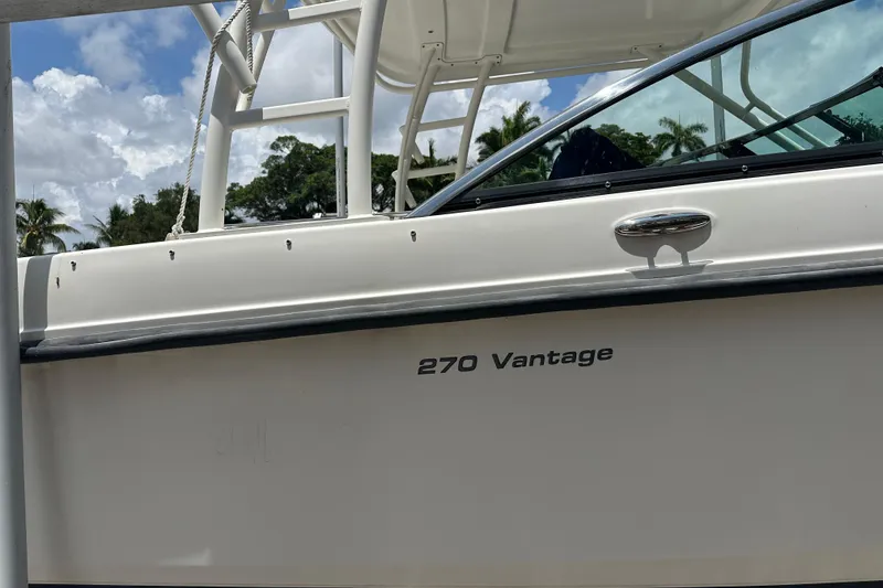 Slide: The Image of 2015 Boston Whaler 270 Vantage boat side view with clear skies and palm trees. - 11